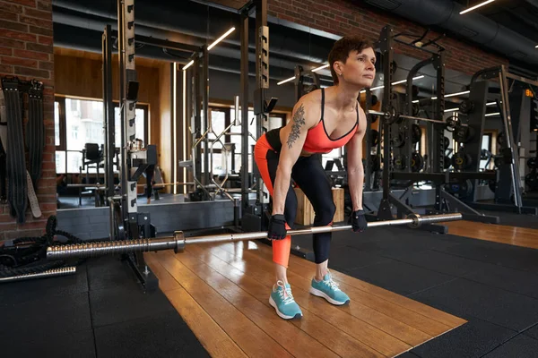 Lugn fokuserad idrottskvinna utför deadlift på gym — Stockfoto