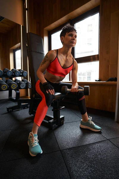 Mujer en forma haciendo ejercicio de brazo sentado en interiores — Foto de Stock