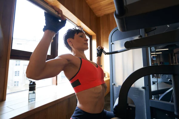Kvinna gör sittande axelpress på träningsmaskin — Stockfoto
