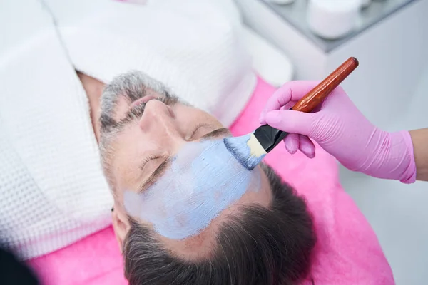 Αισθητικός εφαρμογή μάσκα στο πρόσωπο του πελάτη στο σαλόνι ομορφιάς — Φωτογραφία Αρχείου