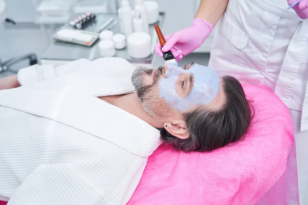 男性の顔にマスクを適用美容室の医師 — ストック写真
