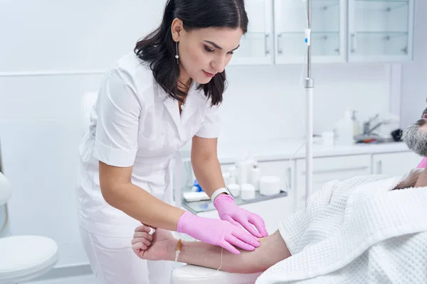 Verzorgende cosmetoloog vrouw bereidt een intraveneuze vitaminedruppelbehandeling voor in schoonheidscentrum — Stockfoto