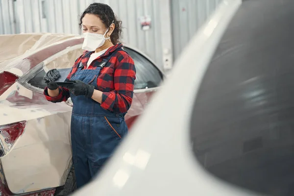 Young concentrated car master looking at spatula — Stock Photo, Image