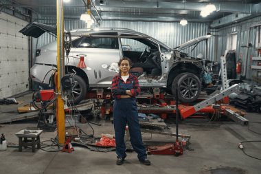 Çalışan kadın otomobil teknisyenleri servis istasyonunda arabanın yanında dikiliyorlar.