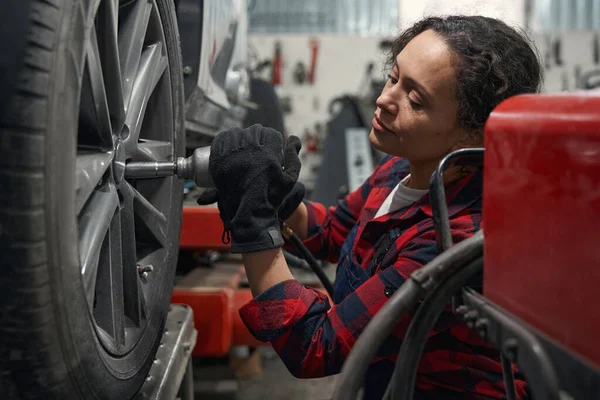 Eldivenli Kadın Araç Teknisyeni Otomobil Tamirhanesinde Tekerleği Tamir Ediyor — Stok fotoğraf