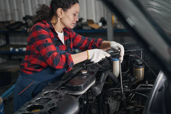 维修站修理汽车发动机时使用扭矩扳手工具时戴工作手套的女技术员 — 图库照片