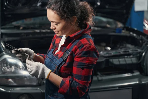 車の修理サービスステーションで金属ラグナットを修復手袋作業中の女性自動車技術者 — ストック写真