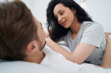 Sevgi dolu bir adamın göğsüne uzanmış, gülümseyen mutlu genç bir kadın.