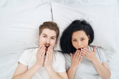 Şok olmuş bir adam ve korkmuş genç bir kadının yatakta yatıp bakışıyla.