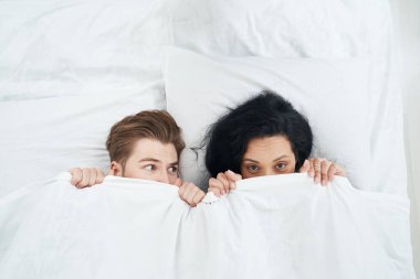 Korkmuş bir adamın yatakta yanında uzanan kadına bakışının en üst görüntüsü.