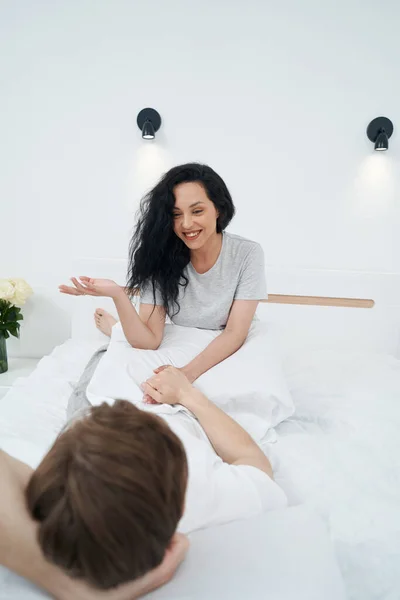 Fröhliche Frau Sitzt Vor Mann Bett Und Spricht Mit Ihm — Stockfoto