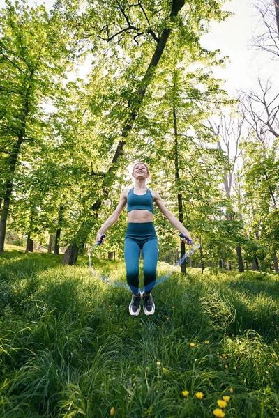 Jolly Ung Smal Kvinna Gör Träning Grönt Trä Och Använda — Stockfoto