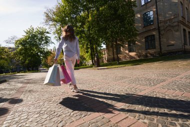 Kadın eski kentte geziyor ve moda mağazalarına alışverişe gittikten sonra alışveriş yapıyor.