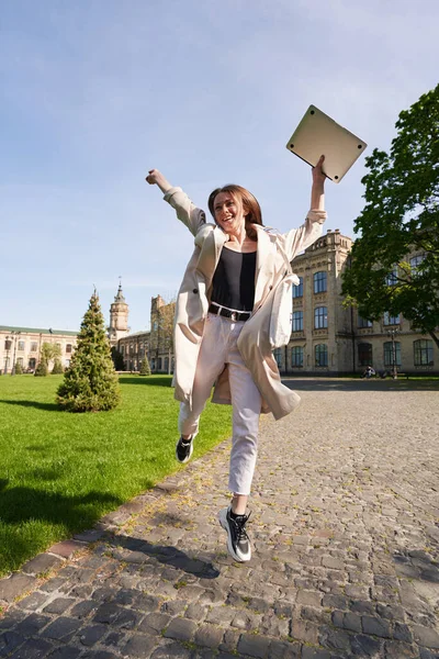 Радостная Юная Леди Проводит Активный День Открытым Небом Прыгает Ноутбуком — стоковое фото