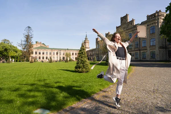 Радостная Молодая Женщина Гуляет Парке Старым Зданием Прыгает Держа Ноутбук — стоковое фото