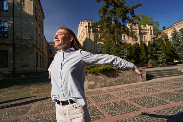 Mutlu çilli kadın, eski kasabada güneşi selamlarken kollarını açıp gözlerini kapatıyor.