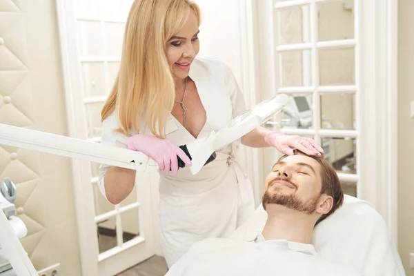 Middelbare Leeftijd Kaukasische Cosmetoloog Vegen Terug Mannelijk Haar Terwijl Schijnend — Stockfoto