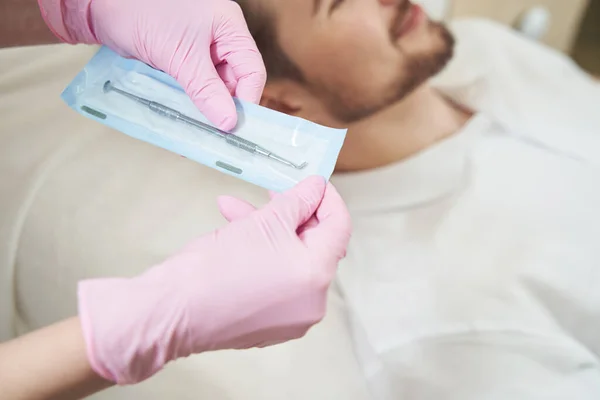 手戴粉色手套 手持包装好的单汤匙工具 清洁躺在病人旁边的毛孔 — 图库照片