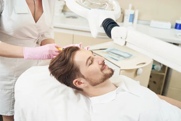 美容师用注射器扎入美容院男病人的头部 — 图库照片