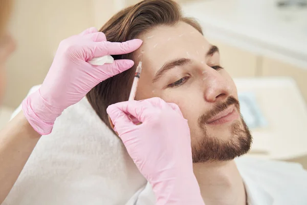 穏やかな白人男性笑顔ながら美容師注入彼の額にボツリヌス毒素 — ストック写真