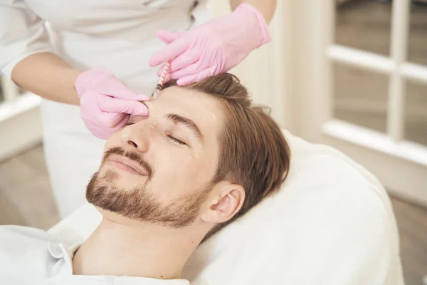 頭にボツリヌス毒素注射のための注射器を使用して美容の専門家が笑顔白人男性のクローズアップ写真 — ストック写真