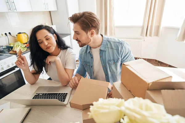 Bilgisayarın başında oturan kız arkadaşıyla konuşan memnun bir mağaza çalışanı.