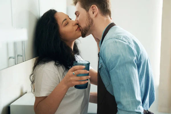 恋爱中的男人吻坐在厨房柜台上的年轻女人 — 图库照片