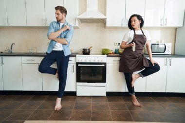 Kızgın ev kadını elinde bıçakla mutfak tezgahında dikilip üzgün kocaya bakıyor.