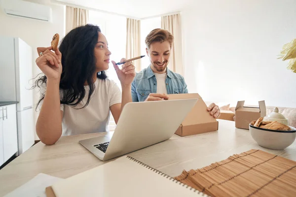 Kvinna Sittande Vid Laptop Stirrar Leende Fokuserad Man Stänga Kartong — Stockfoto