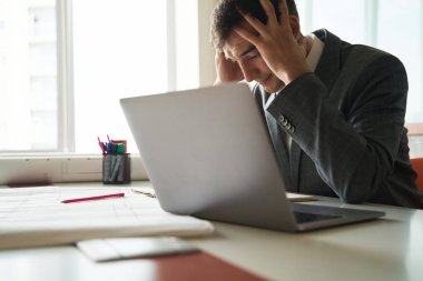 İşte bitap düşmüş bir masa çalışanı ve elleri dizüstü bilgisayarın yanında duruyor.
