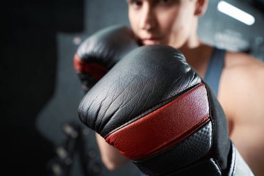 Spor salonunda kameraya poz veren boks eldivenli profesyonel boksör.