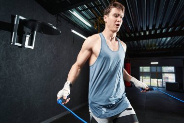 Modern jimnastik salonunda ip atlama eğitimi almış ciddi bir genç adam.