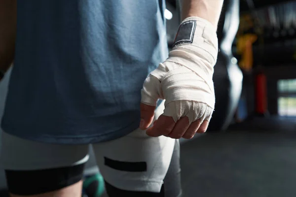 Cropped photo of boxer with hand wrap standing at gym before boxing workout