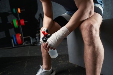 Bir şişe suyla plüton kutusunda oturan sporcunun kesilmiş fotoğrafı.