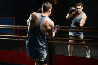 Beden eğitimi sırasında aynanın önünde aparkat atan ciddi odaklı genç sporcu.