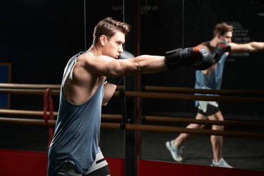 Boks eldivenli bir boksör sağ eliyle yumruk atıyor.