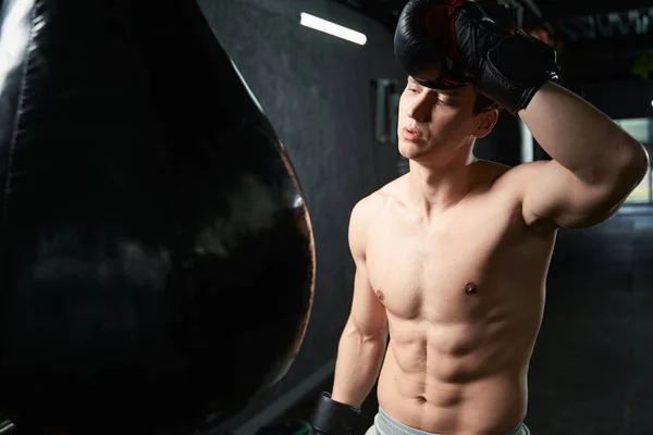 パンチングバッグの前に立つボクシンググローブに身を包んだ若いスポーツマン — ストック写真
