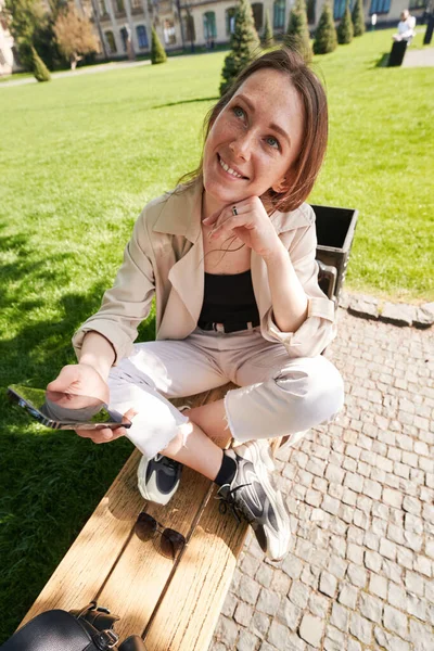 Fröhliche Frau Sitzt Mit Handy Auf Einer Bank Park Während — Stockfoto