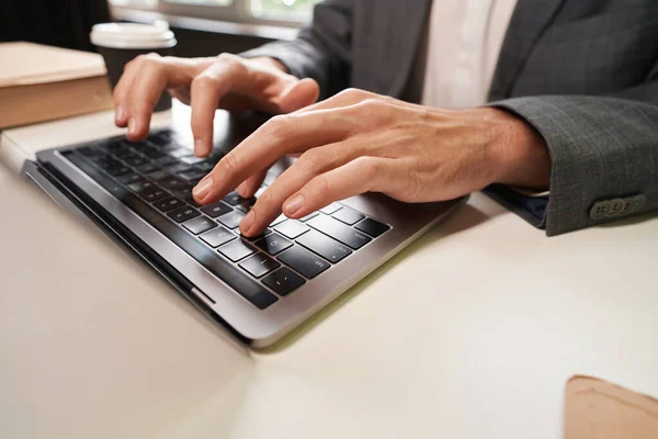 Close-up photo of office worker hands pressing keys on laptop keyboard while typing