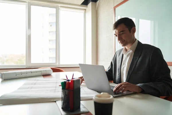 Male Building Designer Working Laptop While Putting Hand Blueprint Front — Stockfoto