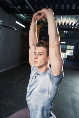 Sakin, genç, kaslı erkek sporcu. Spor salonunda Tepeden Erişilme egzersizi yapıyor.