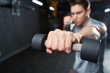 Spor salonunda boks yaparken halterli yumruk atan kararlı erkek boksör.