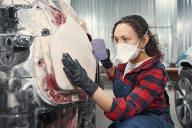 Oto cilalarken dikkatli kadın tamirci atölyede.
