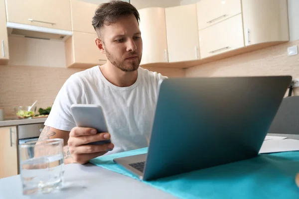 Serious Caucasian Male Dialing Number Mobile Phone While Staring Laptop —  Fotos de Stock