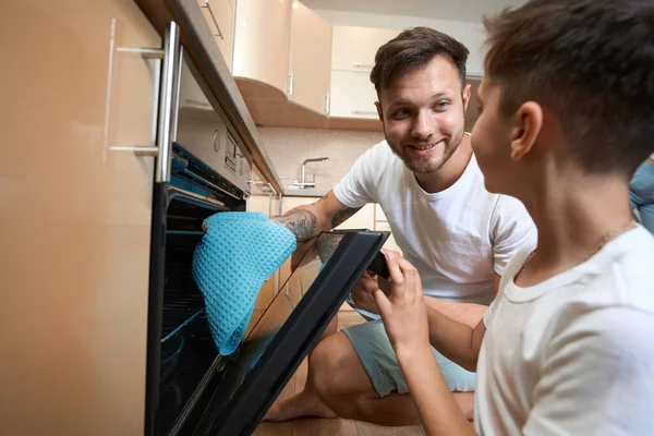 Encouraging Parent Giving Kid Wiping Cloth Cleaning Open Oven Electric —  Fotos de Stock