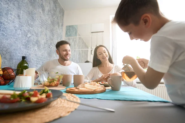 Niño Buscando Para Madre Tetera Inclinada Sobre Taza Durante Comida —  Fotos de Stock