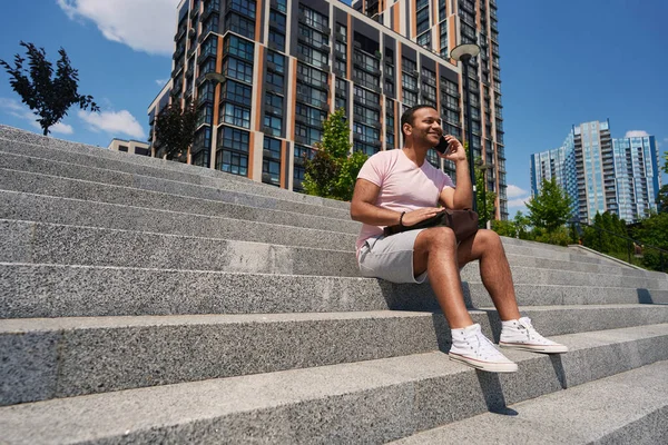 Veselý Mladý Muž Sedí Schodech Mimo Kancelářskou Budovu Během Telefonního — Stock fotografie