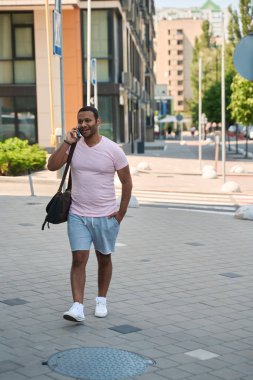 Telefon görüşmeleri sırasında cadde boyunca yürüyen genç erkek portresi