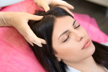 Woman on a massage procedure after mesotherapy relaxes in a chair of an aesthetic medicine center