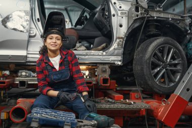 Kaynak yaptıktan sonra dinlenirken metal desteğinde oturan memnun tamirci.